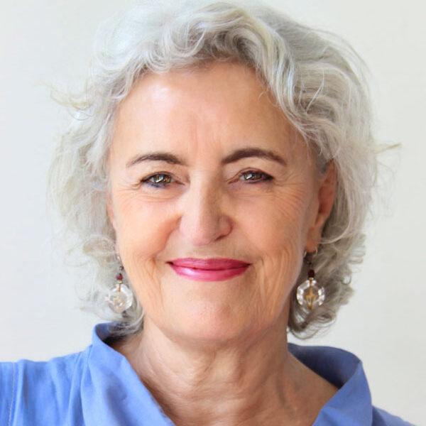Eine Frau mit grauem Haar lächelt in die Kamera und stellt ihre Fähigkeiten in der kraniosakralen Osteopathie zur Schau.